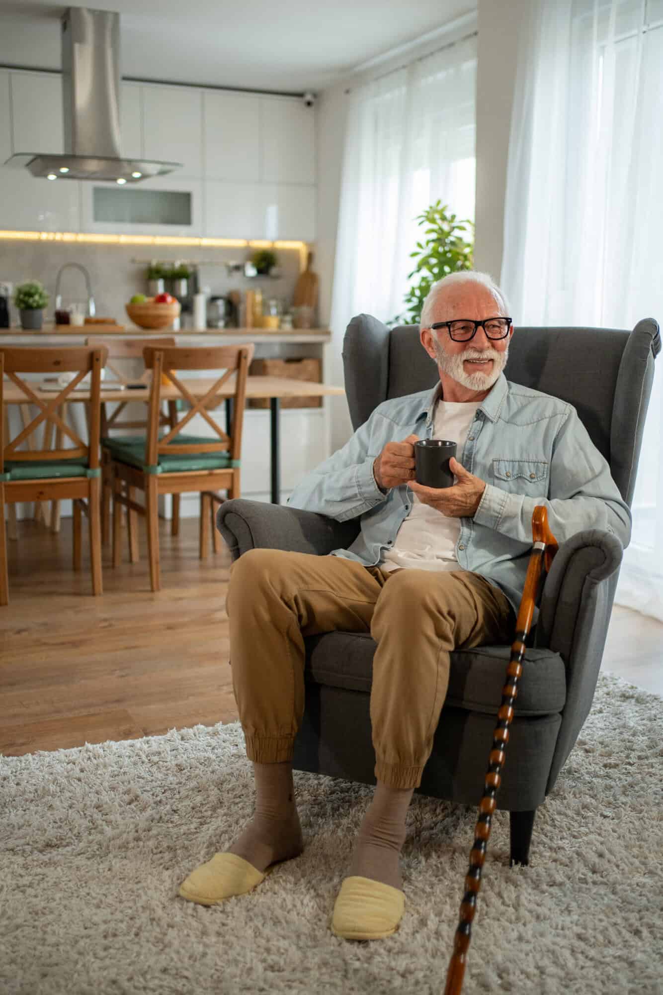 Senior man relaxing at home, enjoying a cup of coffee in an armchair